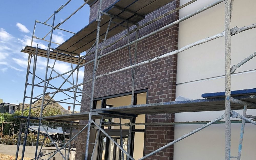 Brick and stucco elevation going up behind scaffold on one of our builds