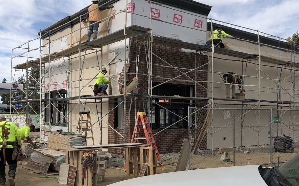 Our crew in high-visibility gear working a scaffolded shell
